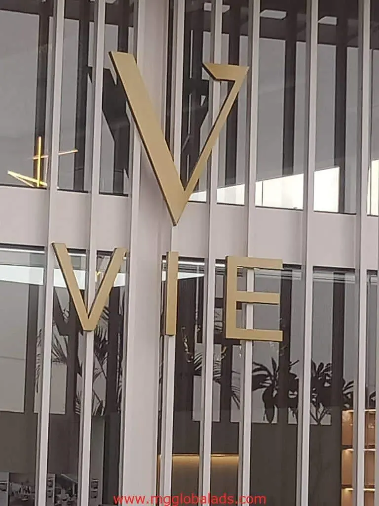 Building signage with large gold VIE letters on glass facade in Makati, modern style, by M&G Global Ads.