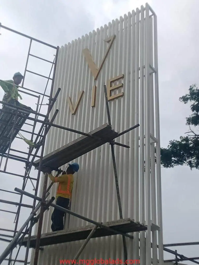 Vertical building signage installation for V VIE in gold letters, outdoor Makati location, by M&G Global Ads.