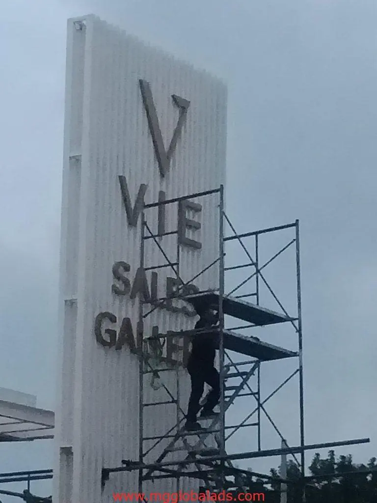 Vertical metal sales gallery signage installation for VIE client in Ortigas, cloudy sky background, by M&G Global Ads.