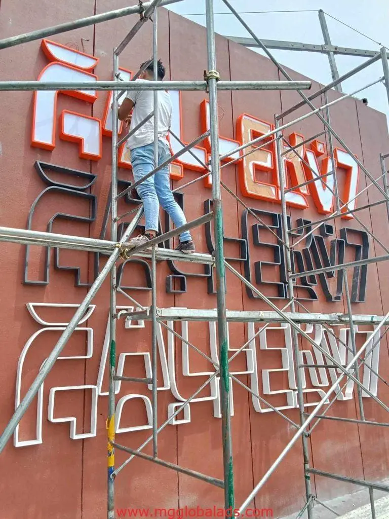 Large LED signage installation on a brown wall in Quezon City, some letters glowing orange, others unlit by M&G Global Ads.