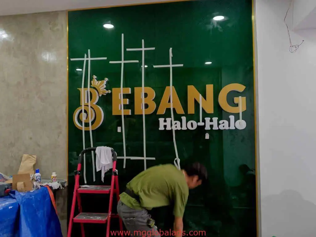 Metallic BEBANG Halo-Halo signage installation in Quezon City with tools and ladder on green wall by M&G Global Ads.