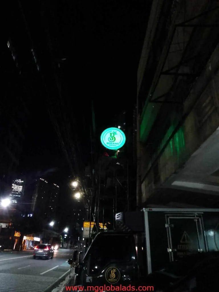 LED signage for 8 Chainz, bright green and circular, on a Makati building at night with traffic by M&G Global Ads.
