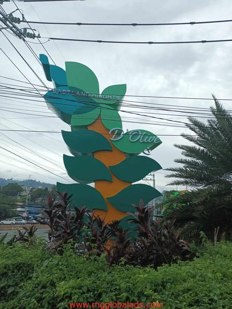 Metal sign for Eastland Heights DOlive beside road in Quezon City, greenery and power lines, by M&G Global Ads.
