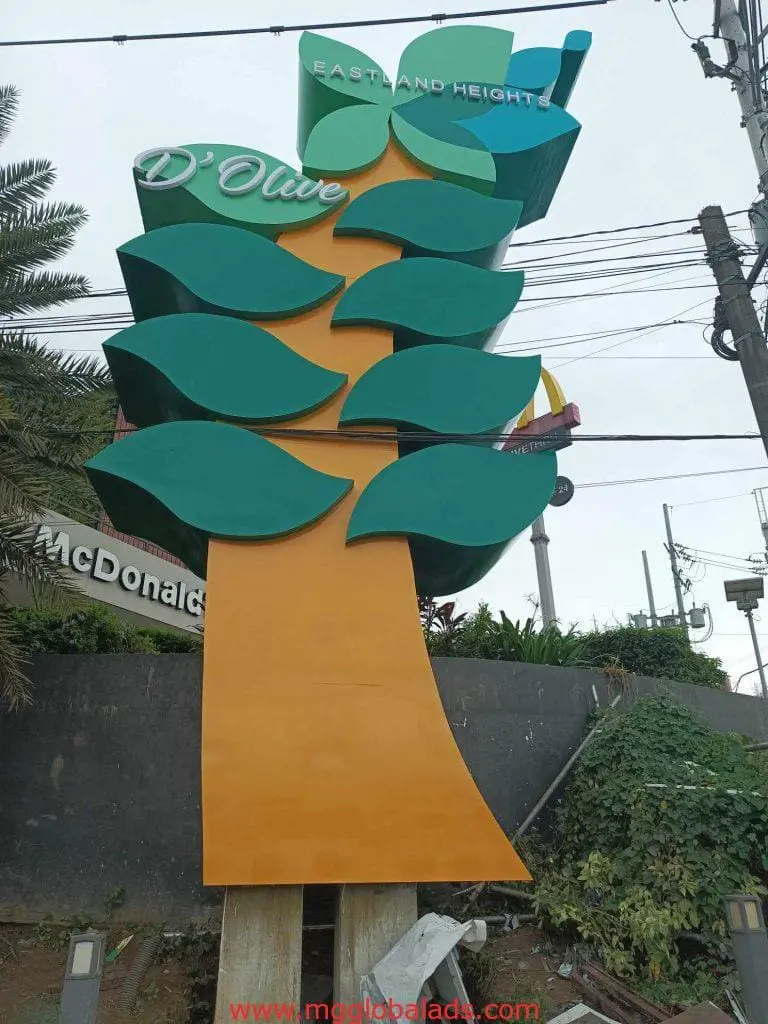 DOlive outdoor tree signage in Quezon City with green leaves, by roadside near McDonalds sign, by M&G Global Ads.