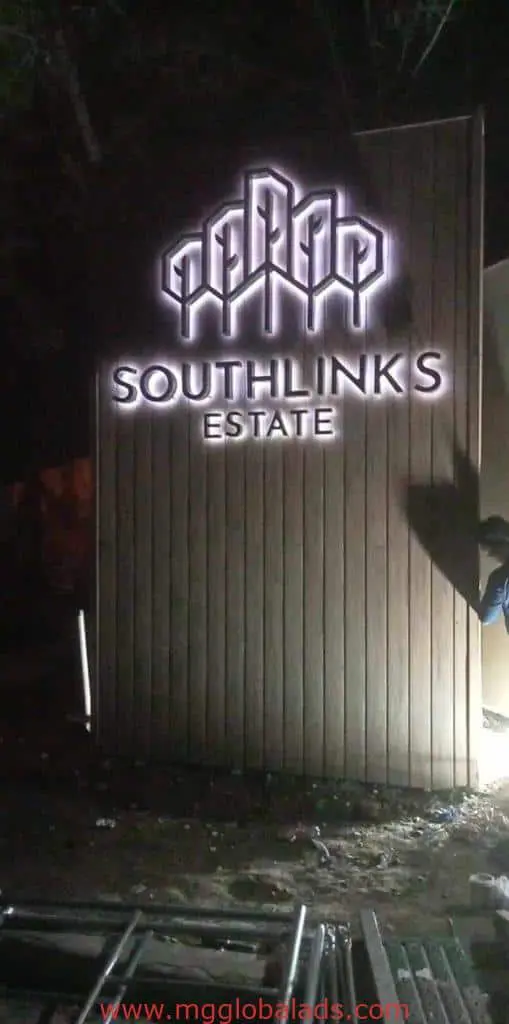 Wooden outdoor illuminated signage for SOUTHLINKS ESTATE in BGC with geometric logo, by M&G Global Ads. Person partially visible.