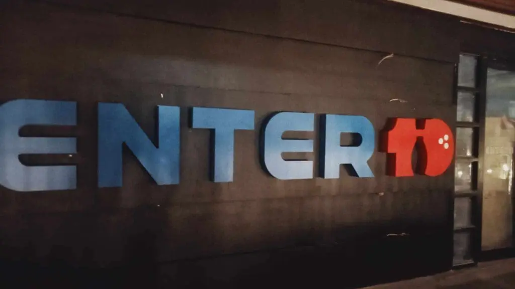Outdoor building signage for ENTER10 with blue and red letters, paw print detail, on dark background in BGC by M&G Global Ads.