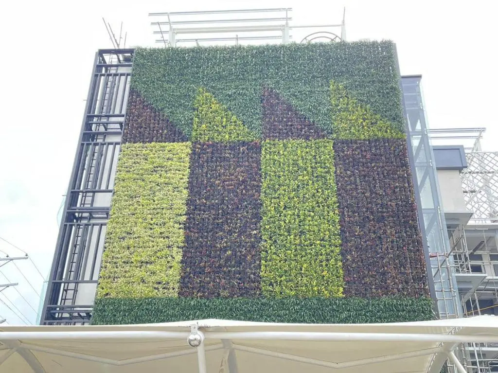 Green wall signage for building in Ortigas with geometric plant pattern, triangles, and scaffolding by M&G Global Ads.