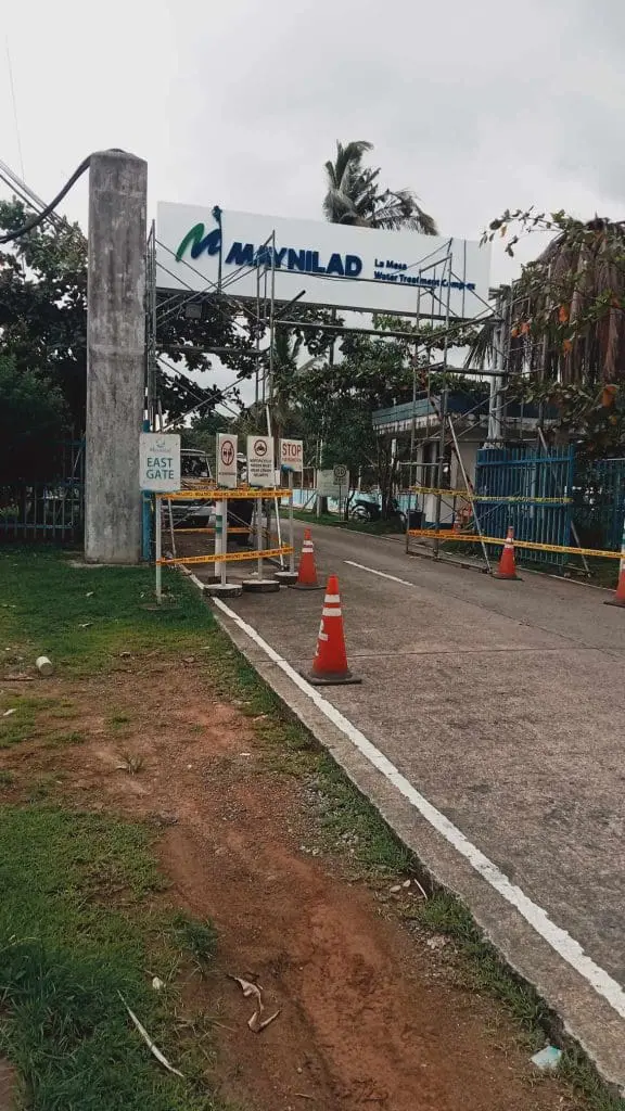 Building entrance sign for Maynilad La Mesa Water Treatment Plant in Quezon City by M&G Global Ads, with cones and barriers.