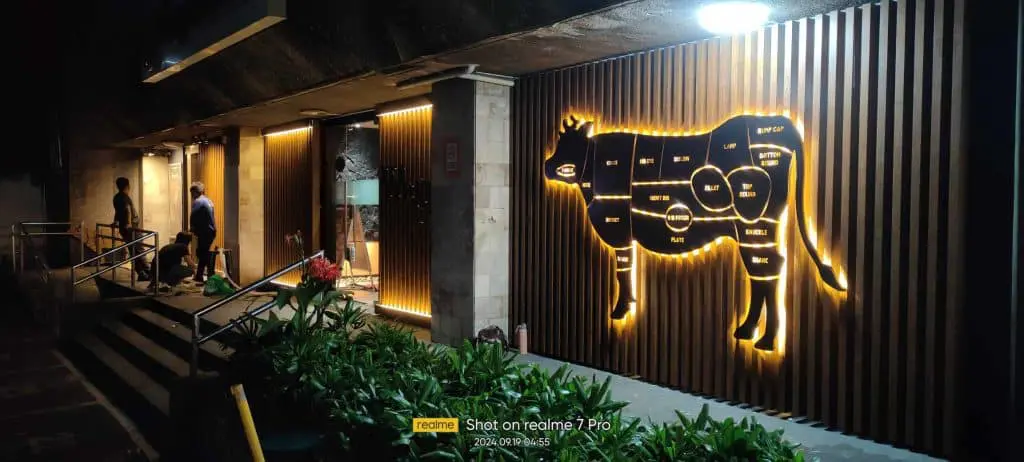 Glowing acrylic cow diagram signage for restaurant meat cuts in BGC at night, inviting entrance by M&G Global Ads.
