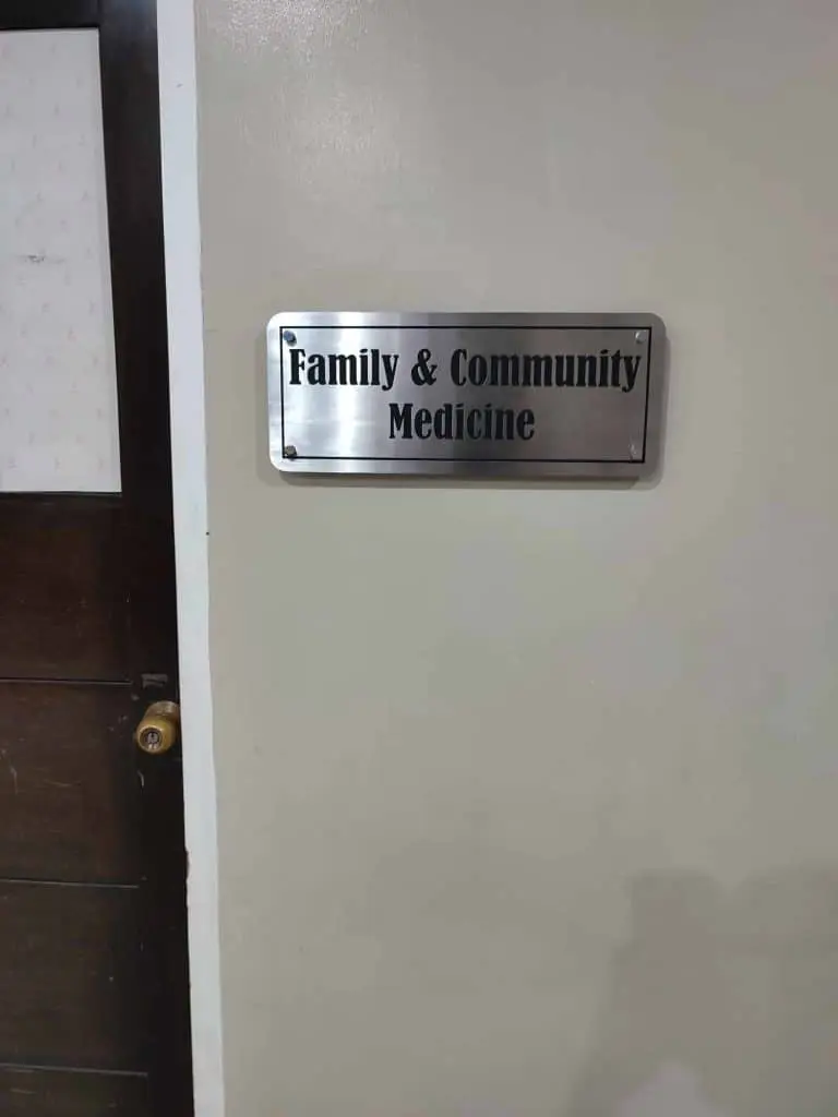Clinic door signage for Family & Community Medicine on beige wall in Makati, wooden door left. By M&G Global Ads.