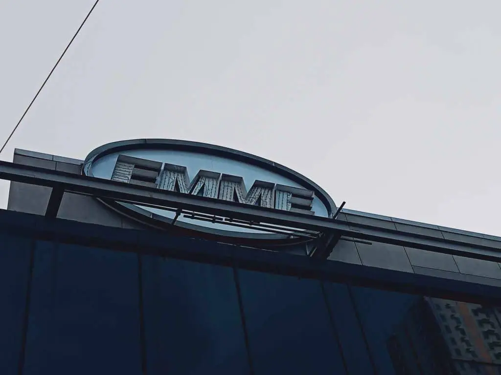 Acrylic building signage for EMME in Makati, modern design, oval sign on glass facade by M&G Global Ads.