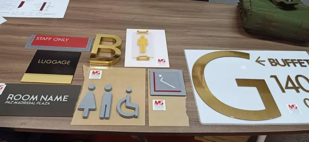 Acrylic and metallic indoor signage for restrooms and rooms in Makati, with accessibility icons by M&G Global Ads.