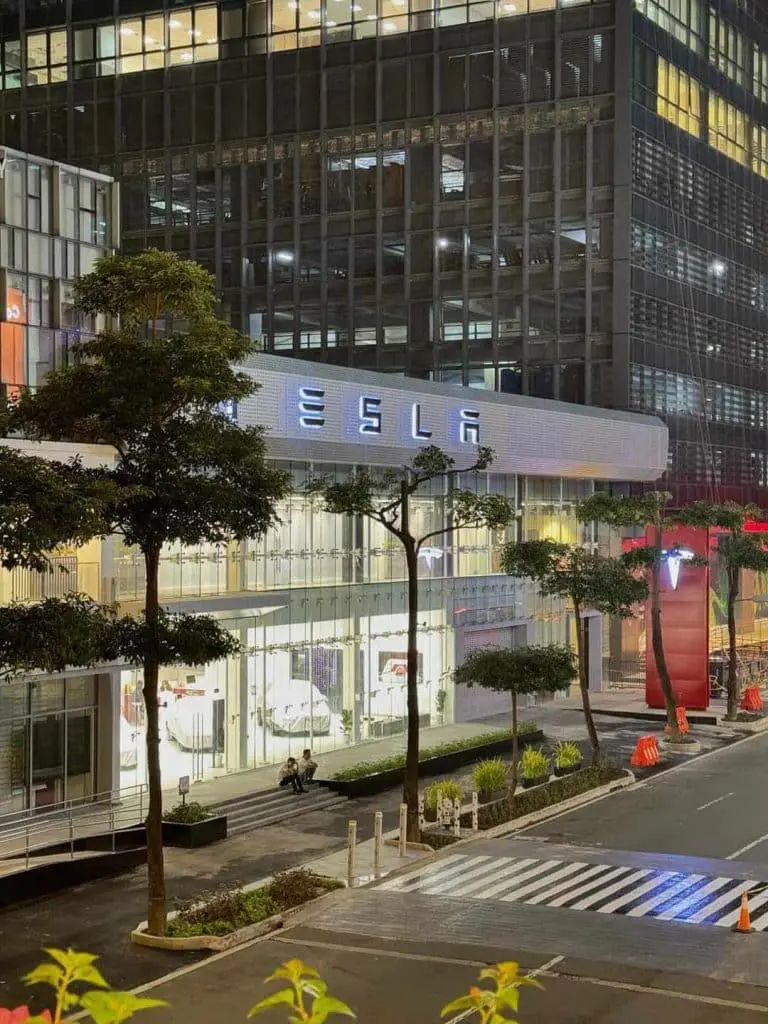 Tesla illuminated building signage for showroom in Makati at night with glass windows and zebra crossing by M&G Global Ads.