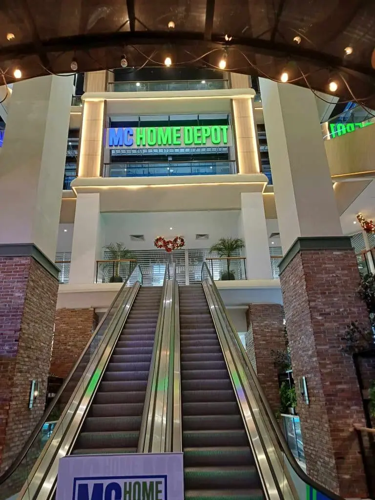 MC Home Depot LED signage above an escalator in a modern mall, Ortigas. Wreaths, plants, brick pillars by M&G Global Ads.