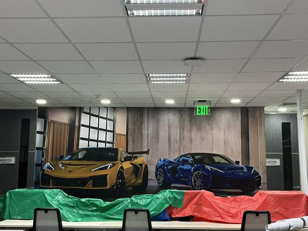Wall mural with sports cars, LED signage in an office with tarped tables, chairs; Ortigas location by M&G Global Ads.