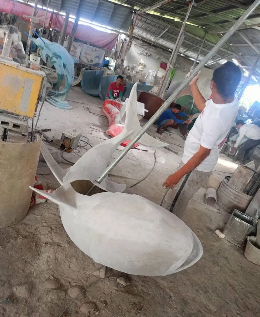 LED signage workshop in Makati, staff sculpting shark display among tools and forms, glowing LED signs by M&G Global Ads.