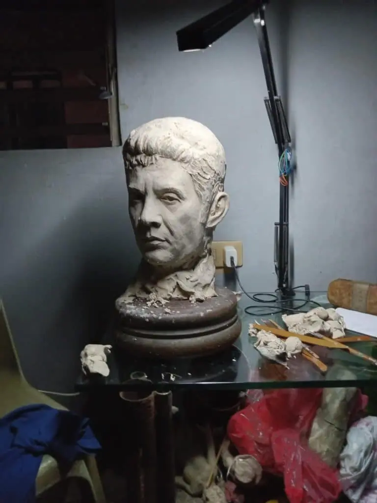 Indoor signage elements with clay bust and sculpting tools on glass table in Makati, artistic studio lighting by M&G Global Ads.