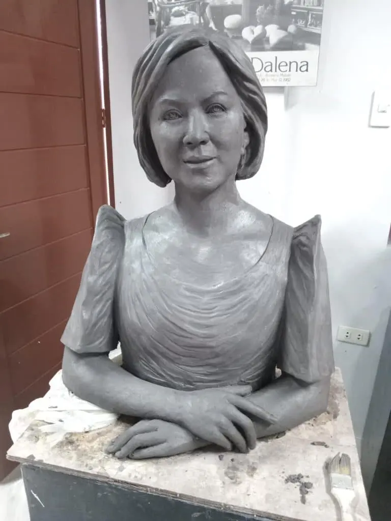 A clay bust of a woman with pleated dress, folded arms, and acrylic signage for a Quezon City client by M&G Global Ads.