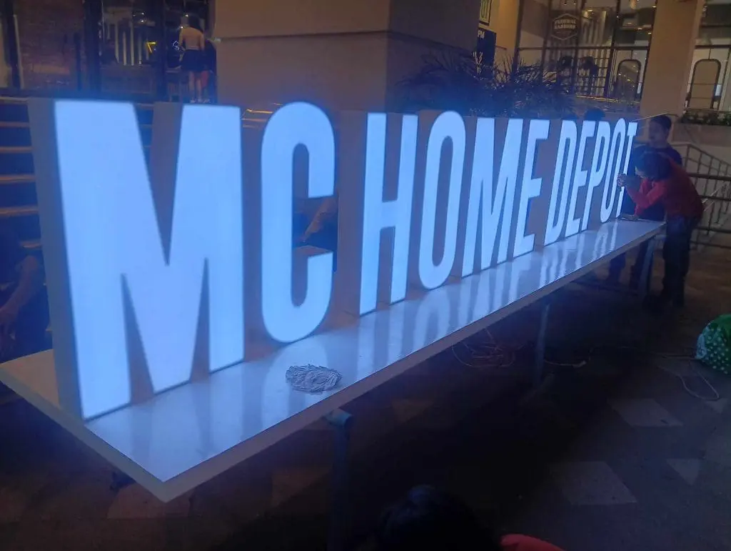 Acrylic Signage Maker in Metro Manila – M&G Global Ads signage for MC HOME DEPOT in Ortigas at night, people nearby; stairs in background.