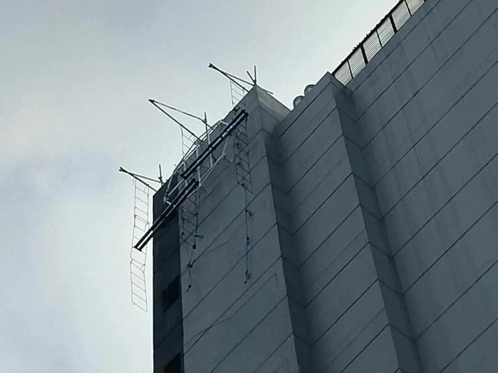 Rooftop billboard signage on a tall building with scaffolding in Makati under an overcast sky by M&G Global Ads.