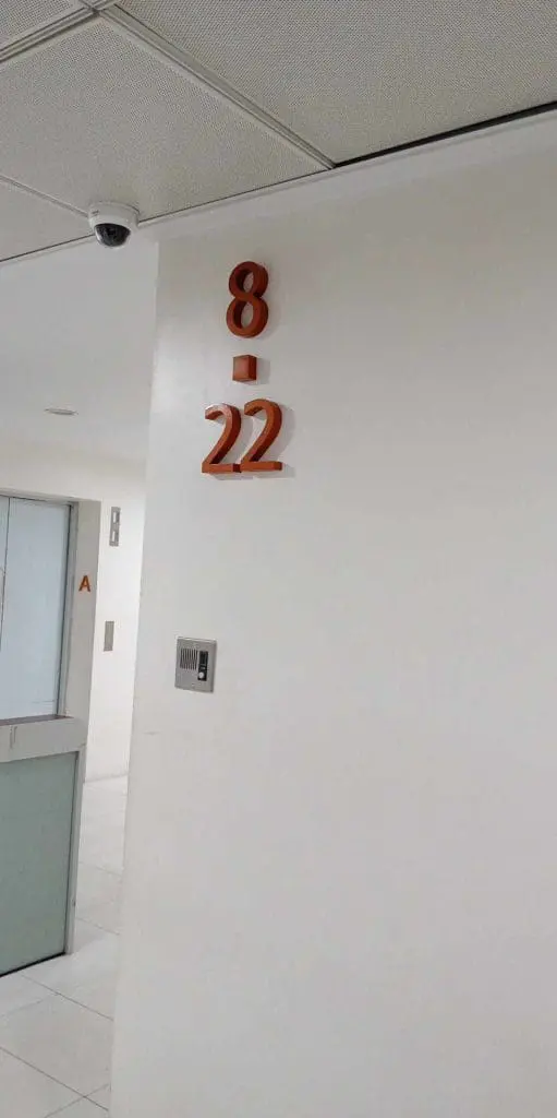 Indoor office wall signage with orange numbers 8-22, security camera, in Makati building hallway by M&G Global Ads.