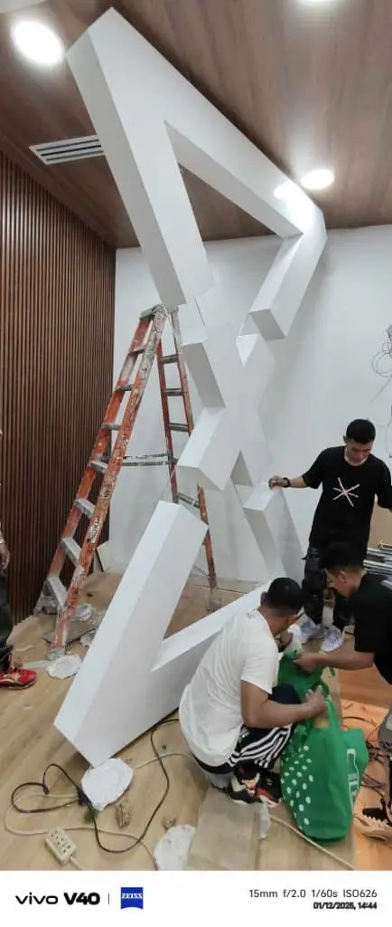 Indoor 3D geometric signage installation with workers and tools in Mandaluyong by M&G Global Ads.