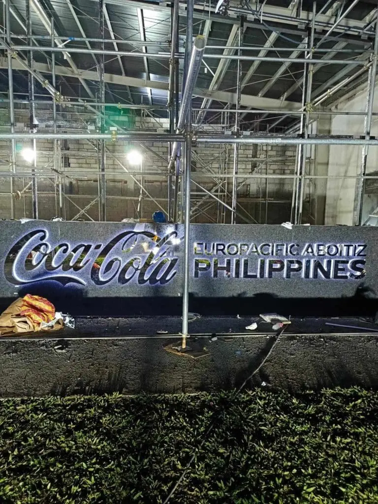 LED signage Coca-Cola Europacific Aboitiz Philippines at construction site Makati, metal scaffolding, grass by M&G Global Ads.