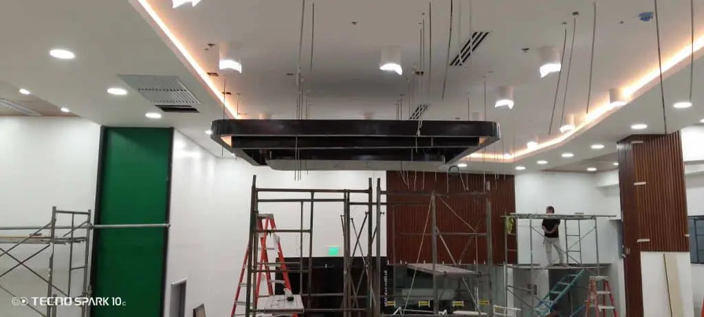 Workers installing illuminated building signage at a modern indoor site in Makati, with scaffolding, by M&G Global Ads.