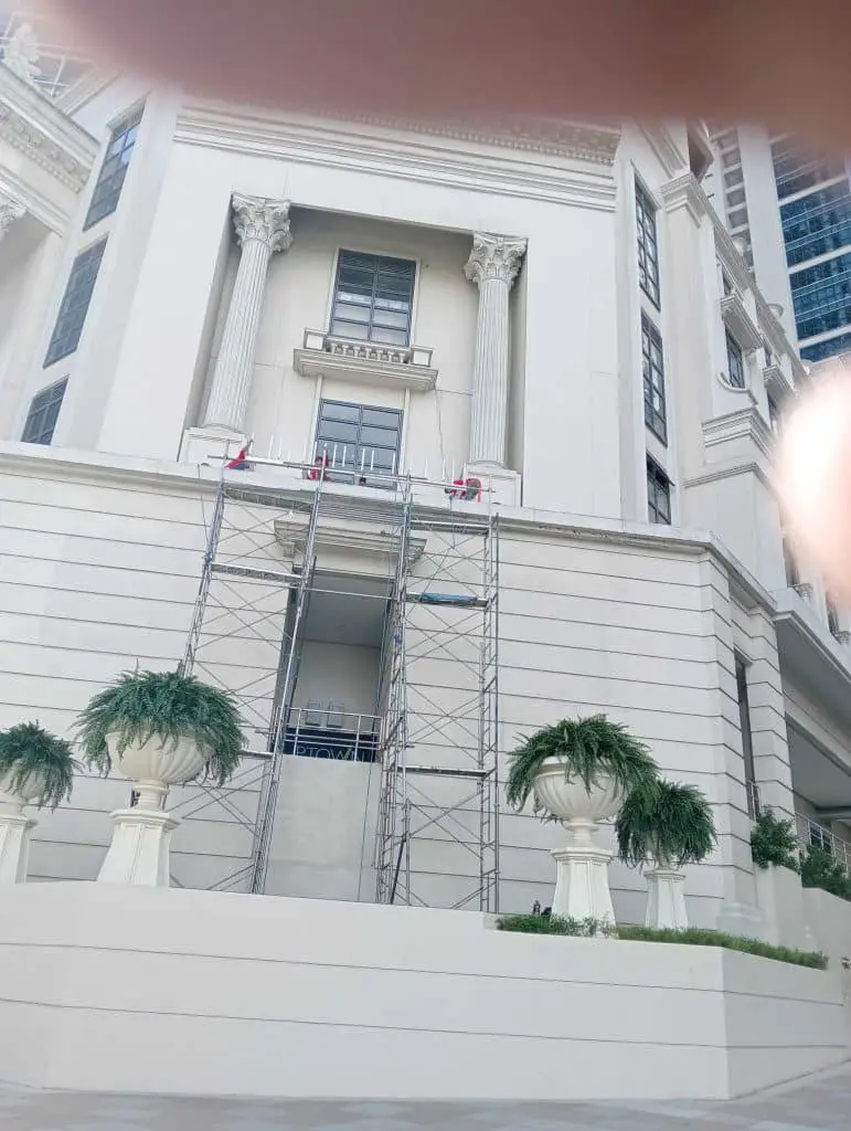 Outdoor building signage installation on a classical white building in Makati with workers on scaffolding by M&G Global Ads.