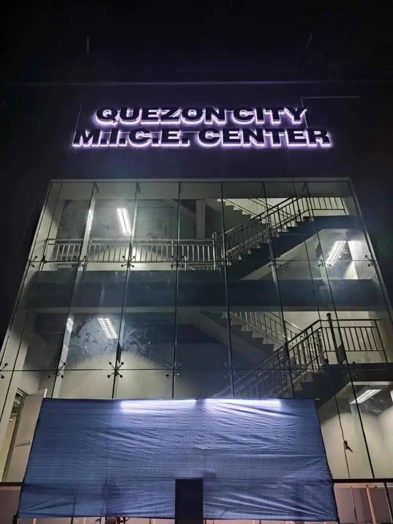 Metallic building sign QUEZON CITY MITCET CENTER facade, glass/staircase view, Cubao at night by M&G Global Ads.