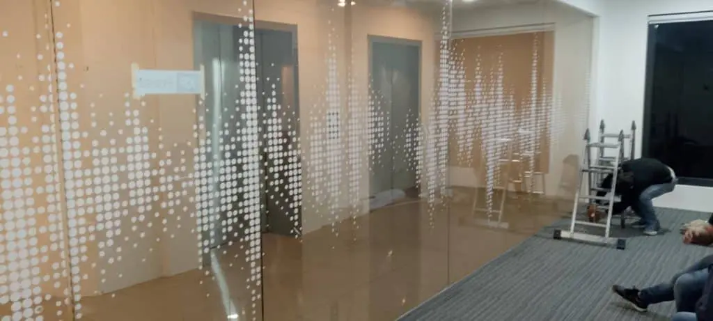 Sleek LED signage in a modern office with glass wall divider in Makati, two workers nearby, by M&G Global Ads.