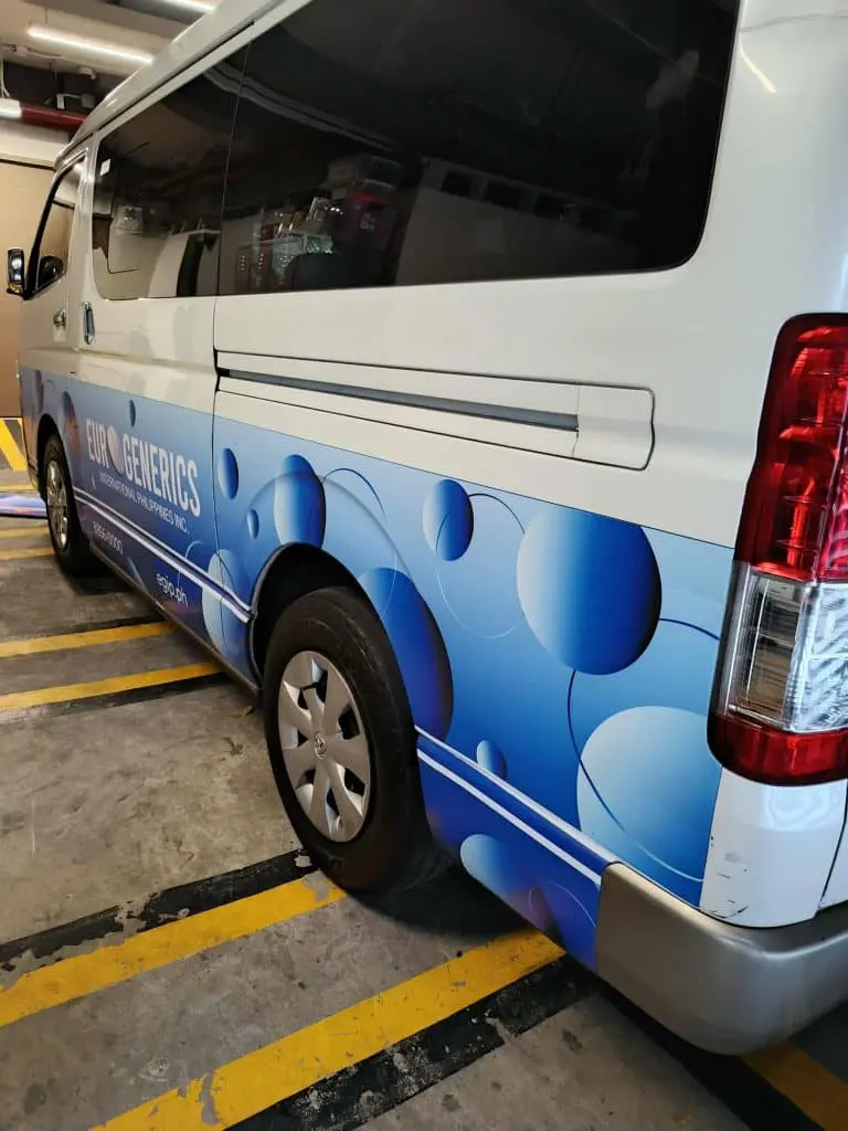 Metallic signage for EUR-GENERICS beside white van in indoor Makati lot, blue circles visible—by M&G Global Ads.