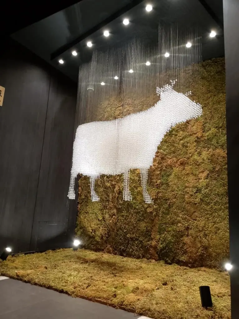 Indoor acrylic signage of a cow silhouette with white discs against a moss wall, spotlighted in Metro Manila by M&G Global Ads.