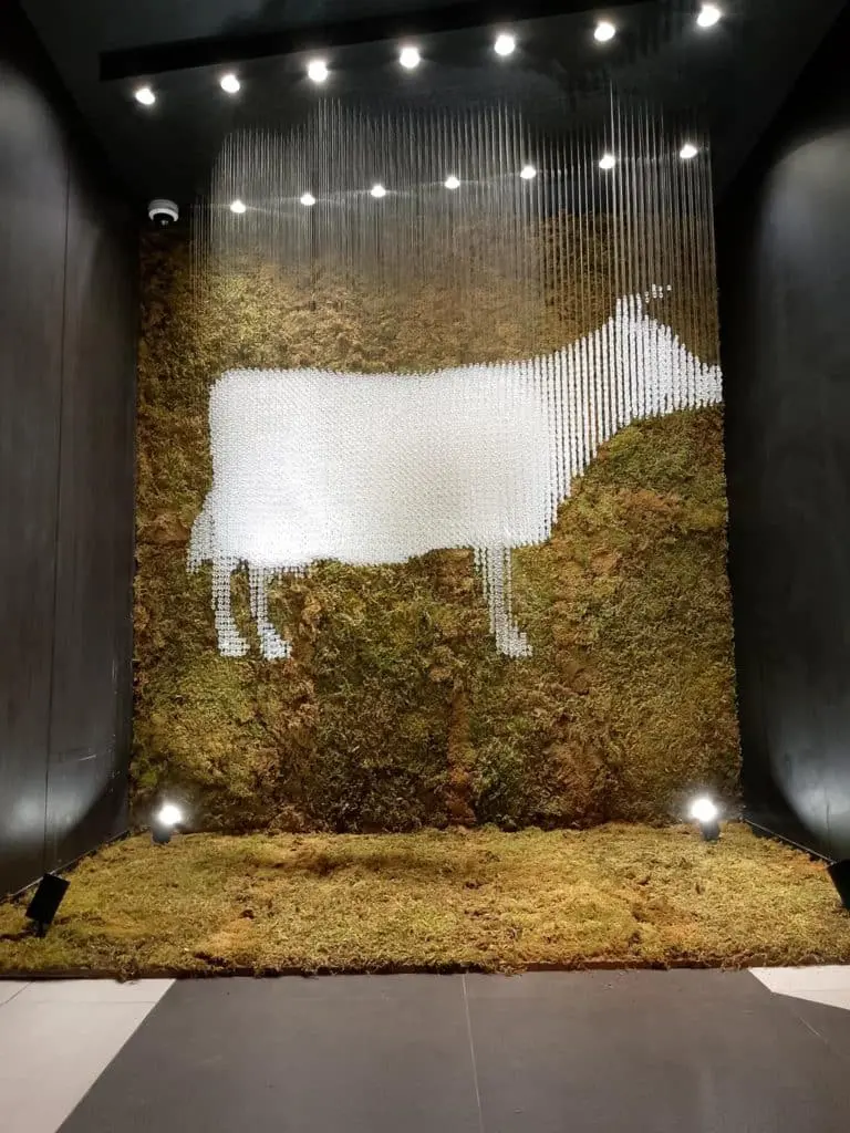 Indoor signage in Metro Manila of a cow silhouette made from white rods and moss wall, artfully lit by M&G Global Ads.
