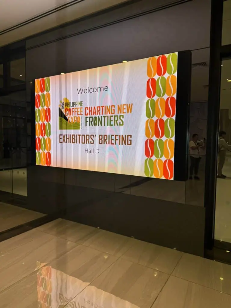 Digital signage for Philippine Coffee Expo at Hall D with coffee bean patterns, Makati. Vibrant floor reflection by M&G Global Ads.