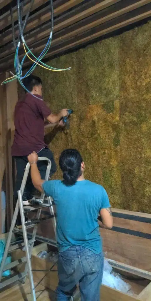 Indoor moss wall installation in Metro Manila; workers using power tools, exposed beams. Sign maker Philippines by M&G Global Ads.
