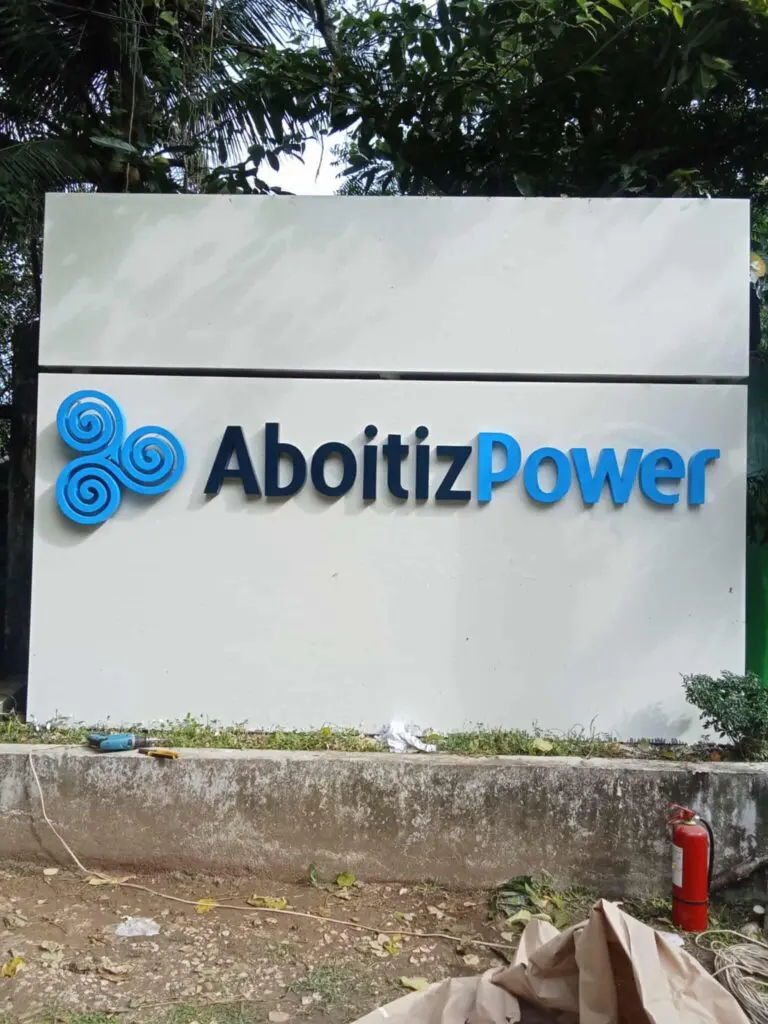 AboitizPower outdoor signage in Makati with blue logo, greenery, and fire extinguisher by M&G Global Ads.