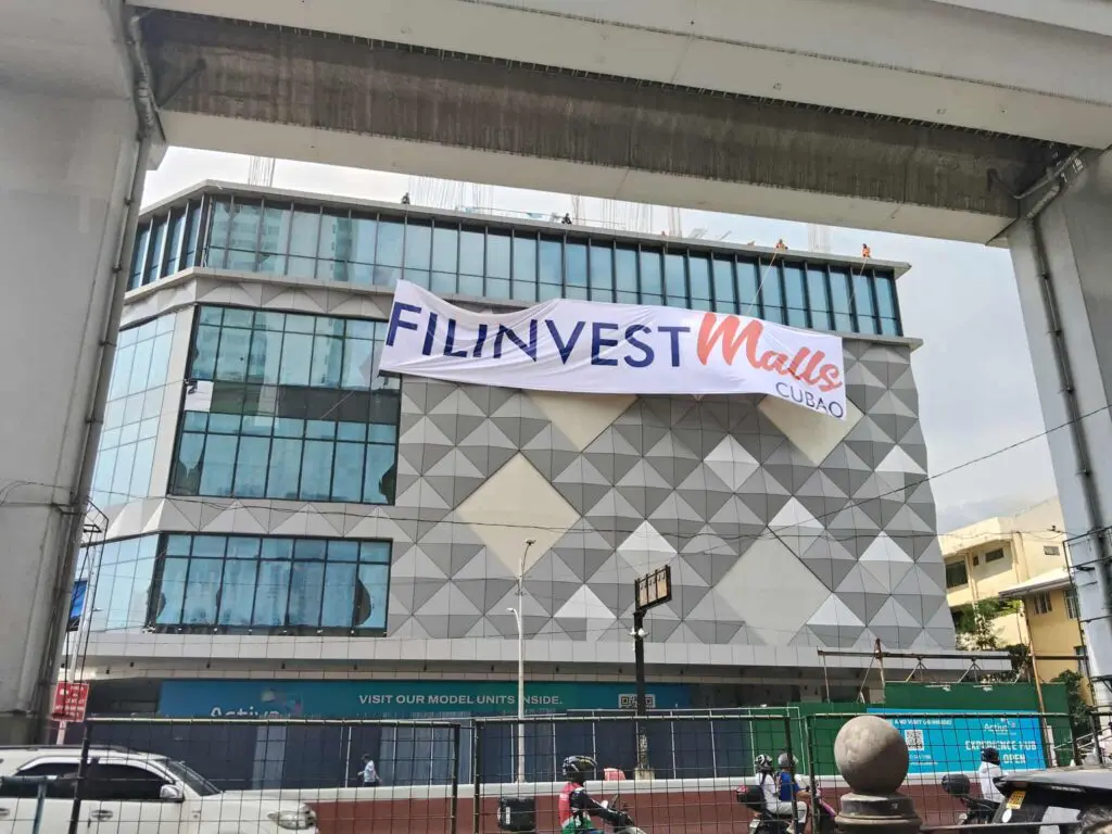 Large building banner signage for FILINVEST Malls at Cubao, Quezon City, with street view and rail, by M&G Global Ads.
