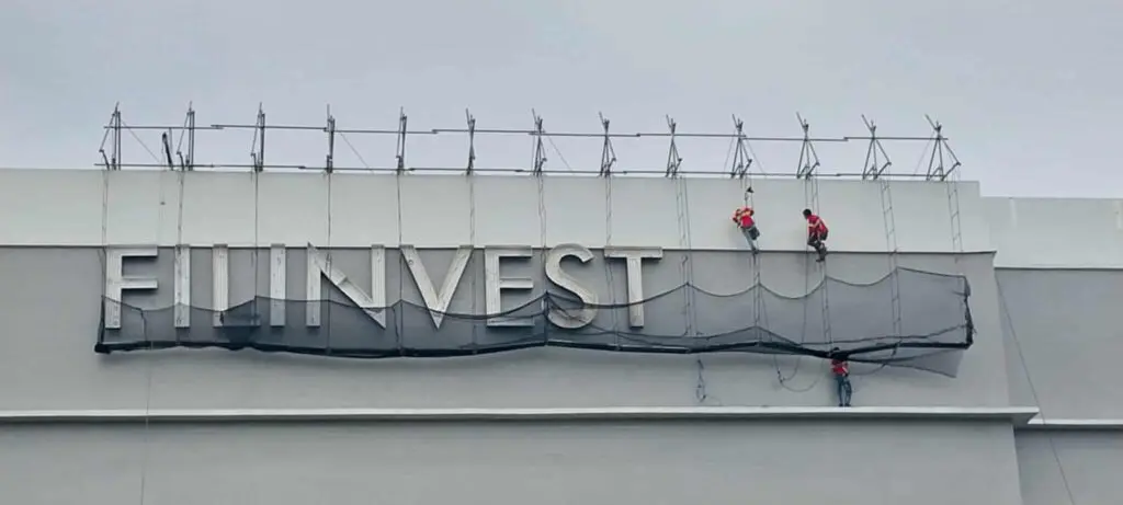 Workers install an outdoor acrylic FILINVEST building sign, Metro Manila. Sign maker Philippines by M&G Global Ads.
