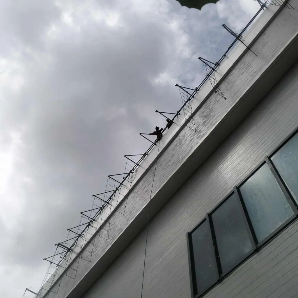 Sign maker Philippines: workers install building signage with cables on tall white building, Metro Manila, by M&G Global Ads.