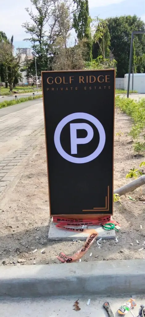 Outdoor parking signage for Golf Ridge Private Estate featuring a black acrylic sign with a large white "P" parking symbol, positioned beside a paved road with trees and buildings visible in the background, located in the Philippines. Sign maker Philippines by M&G Global Ads.