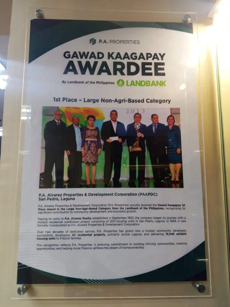 Acrylic indoor signage poster for P.A. Properties, announcing their 1st Place Large Non-Agri-Business Gawad Kaagapay Award by Landbank, featuring a group photo of six people onstage holding a trophy; sign maker Philippines by M&G Global Ads. Location: Philippines.