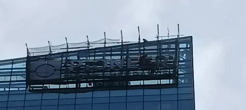 Sign maker Philippines installing outdoor acrylic building signage reading PIONEER on glass facade, Metro Manila by M&G Global Ads.