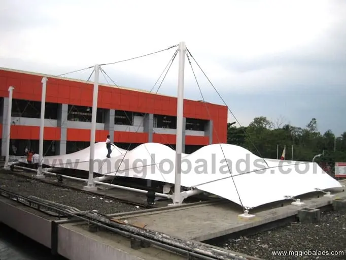 Outdoor building signage with white tensile fabric canopy, rooftop poles, orange and white facade, sign maker Philippines by M&G Global Ads.