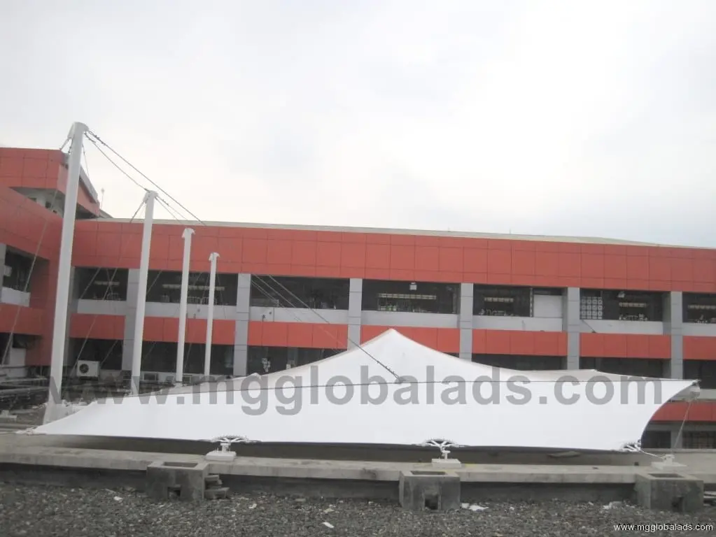 Outdoor building signage with a large white tensile fabric canopy in front of a red and gray structure, sign maker Philippines by M&G Global Ads.