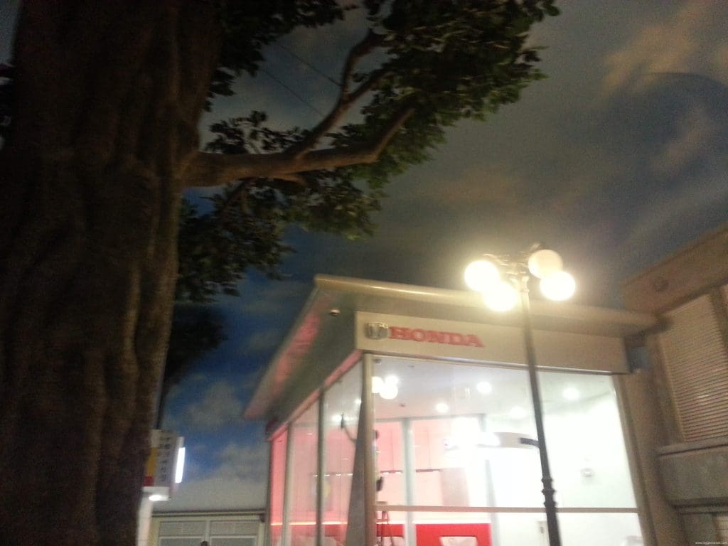 Honda glass building signage in Makati with a large tree, cloudy sky, and streetlamp—by M&G Global Ads.