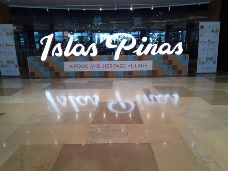 Illuminated acrylic signage for Islas Pinas food and heritage village in a modern Cubao venue, colorful background, by M&G Global Ads.
