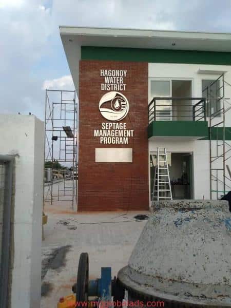 Hagonoy Water District stainless signage on building under construction in Mandaluyong, scaffolding and ladders outside by M&G Global Ads.