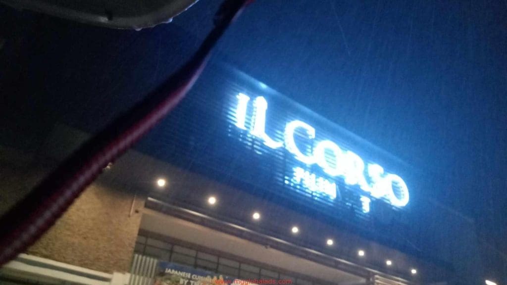 Neon IL CORSO building signage at night in Makati, rain falling, red blur above. Signage by M&G Global Ads.