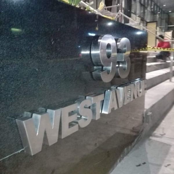 Building address stainless signage 93 WEST AVENUE on dark stone wall in Quezon City at night by M&G Global Ads.